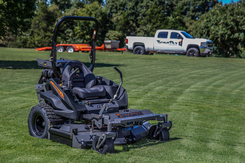 Spartan mower sitting on lawn with truck in background