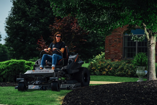 Woman mowing yard with brick house in background