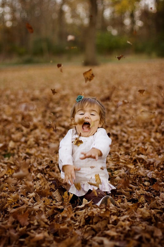 Kid playing in the leaves in fall