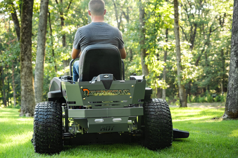 Rear view of man driving RZ mower around trees